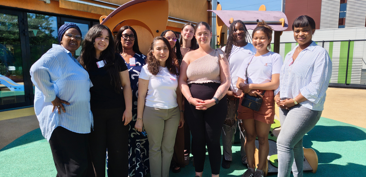 Group of diverse women standing together on a playground, smiling at the camera.