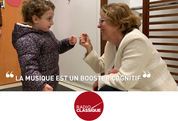 Child and older woman smile and fist-bump; the French quote 'La musique est un booster cognitif' appears with the Radio Classique logo below.